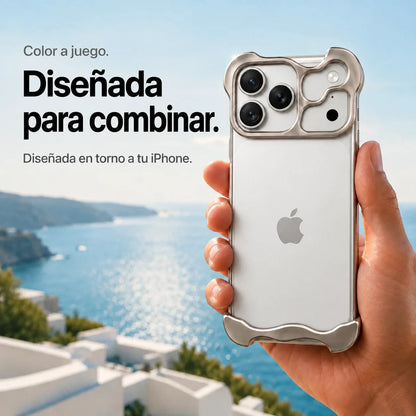 Warm gray sculpted metal phone case held in a hand above a coastal background #color_Natural Titanium
